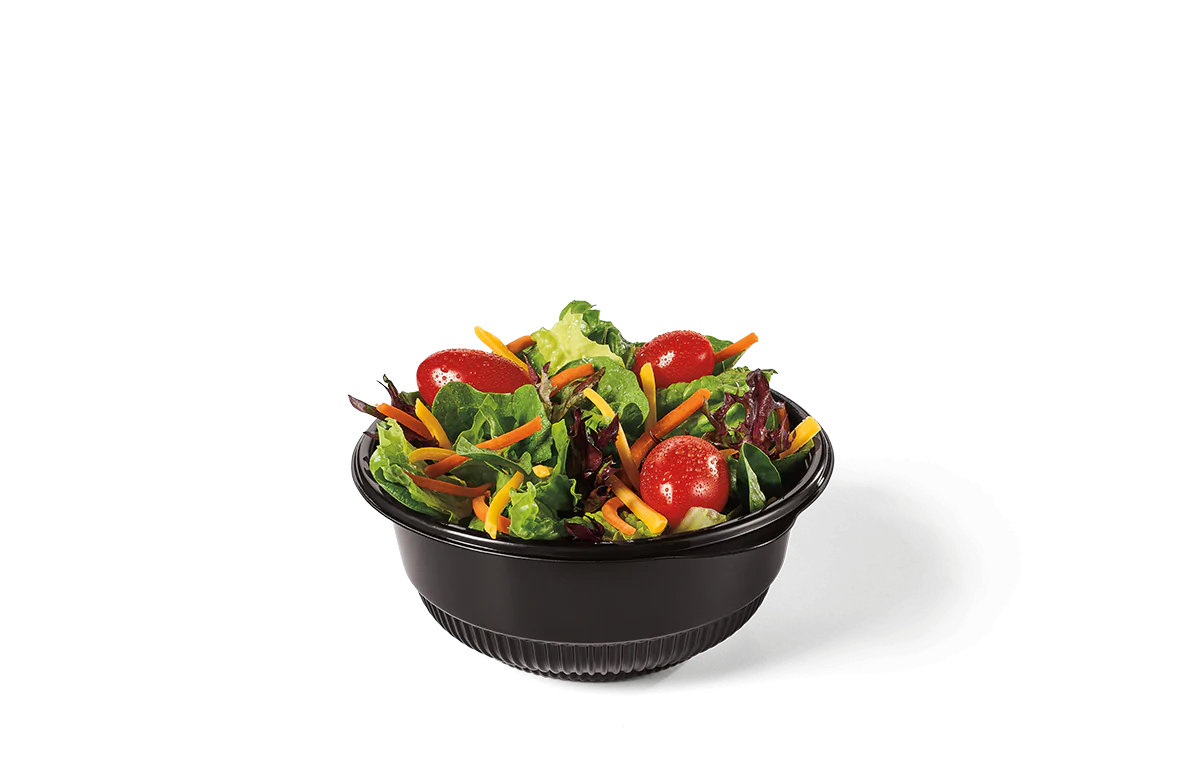 Fresh side salad with mixed greens, cherry tomatoes, shredded carrots, and cucumber slices, served in a bowl